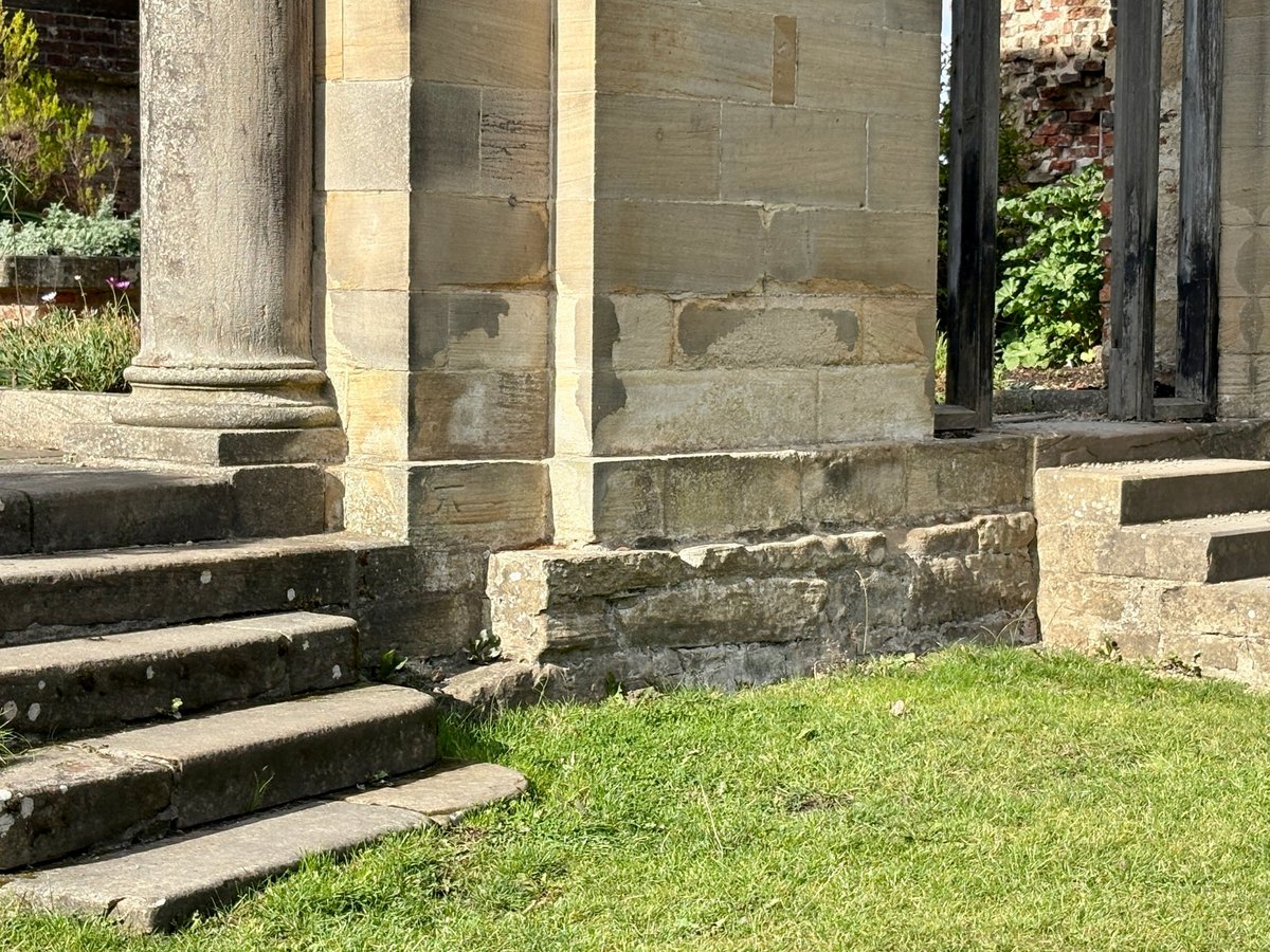Weathered stone steps rise toward a grand old building, its tall pillars casting long shadows while worn edges hint at centuries of footsteps ascending toward the stately entrance ahead to greet time.