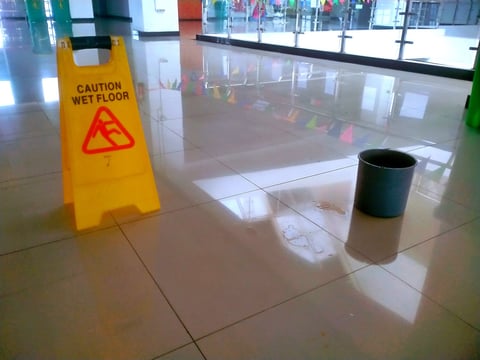 Wet ceramic tile floor with caution sign - kitchen slip hazard
